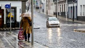 Uma popular protegida por um guarda-chuva passa pela rua do Galo, deserta de pessoas, devido aos efeitos que já estão a ser sentidos, com o aumento gradual do vento e chuva nos grupos central e oriental do arquipélago dos Açores, da passagem do furacão Alex, na Praia da vitória, Ilha Terceira, 15 de janeiro de 2016. Segundo o IPMA  Instituto Português do Mar e da Atmosfera, o período mais crítico ocorrerá entre as 08:00 e as 11:00 de hoje (hora local, menos uma hora do que em Lisboa), quando se prevê a sua passagem em cima do arquipélago. ANTÓNIO ARAÚJO/LUSA