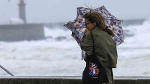 Uma mulher tenta proteger-se da chuva e do vento na marginal da Foz do Douro no Porto, 17 de outubro de 2023. Mais de 40 ocorrências foram registadas desde as 00:00 de hoje, a maioria na Grande Lisboa e em Setúbal, devido ao mau tempo, segundo informação disponível no ‘site’ da Autoridade Nacional de Emergência e Proteção Civil (ANEPC). ESTELA SILVA/LUSA