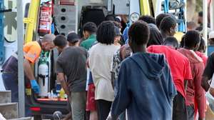 epa13150614 Migrants queue to receive medical attention at El Trampolin beach in Ceuta, Spain, 04 August 2026. According to Spanish officials, around 2,500 migrants remain in Ceuta following last week's massive border rush from Morocco, with many living in overcrowded reception centers or sleeping outdoors on beaches and in parks.  EPA/REDUAN