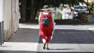Uma mulher caminha num bairro residencial perto da Praça de Londres, em Lisboa, 14 de agosto de 2025. verão. ANTÓNIO PEDRO SANTOS/LUSA