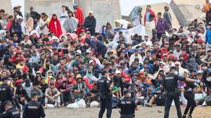 epaselect epa13182348 Several policemen stand guard near a group of migrants at El Trampolin beach in Ceuta, Spain, 21 August 2026. Authorities in Spain's North African enclave of Ceuta cleared migrants from El Trampolin beach for the second time on 21 August, grouping them in one area while crews cleaned the site. The Spanish government is providing temporary shelter for 1,800 migrants sleeping rough on Trampolin Beach and in the Loma Colmenar area of Ceuta, and plans to gradually expand these facilities.  EPA/REDUAN