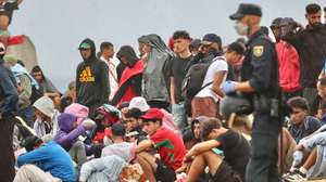 epa13182414 Several policemen stand guard near a group of migrants at El Trampolin beach in Ceuta, Spain, 21 August 2026. Authorities in Spain's North African enclave of Ceuta cleared migrants from El Trampolin beach for the second time on 21 August, grouping them in one area while crews cleaned the site. The Spanish government is providing temporary shelter for 1,800 migrants sleeping rough on Trampolin Beach and in the Loma Colmenar area of Ceuta, and plans to gradually expand these facilities.  EPA/REDUAN