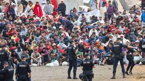 epaselect epa13182348 Several policemen stand guard near a group of migrants at El Trampolin beach in Ceuta, Spain, 21 August 2026. Authorities in Spain's North African enclave of Ceuta cleared migrants from El Trampolin beach for the second time on 21 August, grouping them in one area while crews cleaned the site. The Spanish government is providing temporary shelter for 1,800 migrants sleeping rough on Trampolin Beach and in the Loma Colmenar area of Ceuta, and plans to gradually expand these facilities.  EPA/REDUAN