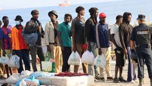 epaselect epa13179896 A police officer (R) escorts migrants from the Trampolin beach to a shelter in Ceuta, Spain, 20 August 2026. The Spanish government is providing temporary shelter for 1,800 migrants sleeping rough on Trampolin Beach and in the Loma Colmenar area of Ceuta, and plans to gradually expand these facilities.  EPA/REDUAN