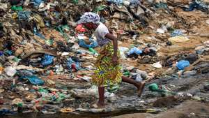 Uma mulçher atravessa uma vala onde se acumulam detritos e águas paradas no Bairro Paraíso, conhecido pelos níveis elevados de pobreza e criminalidade, a doença e a morte vieram afligir ainda mais os moradores, em Luanda, 09 de janeiro de 2025. Pelo menos cinco pessoas foram oficialmente proclamadas vítimas de cólera, doença ligada à contaminação fecal associada à falta de saneamento e tratamento de água e má higiene, e os habitantes estão preocupados pedindo a intervenção das autoridades angolanas. (ACOMPANHA TEXTO DA LUSA DO DIA 12 DE JANEIRO DE 2025). AMPE ROGÉRIO/LUSA