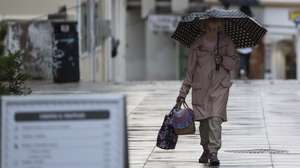 Mulher com chapéu de chuva na Costa de Caparica, Almada, 4 de novembro de 2024. CARLOS M. ALMEIDA/LUSA