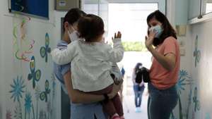 epa08429358 A mother waves to her daughter on the first day after the relief of emergency measures due to the pandemic situation of covid-19, the kindergarten (from 0 to 3 years) start receiving children with some safety measures such as the mandatory wearing of masks by educators, in Porto, Portugal, 18 May 2020. On 15 May, the government approved new measures that come into force on 18 May, including the resumption of visits to users of old people's homes, the reopening of creches, face-to-face classes for the 11th and 12th grade and the reopening of some street shops, cafes, restaurants, museums, monuments, and palaces. The return of the community religious ceremonies is planned for 30 May and the opening of the beaches for 06 June.  EPA/ESTELA SILVA