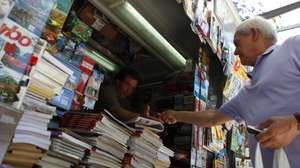 Um popular compra os jornais num quiosque de venda de revistas e jornais, em Lisboa, 13 de julho de 2013. Nos últimos anos, na Avenida da Liberdade, em miradouros pelas sete colinas, nos jardins, à beira Tejo, nas praças, os quiosques foram nascendo ou ganhando vida “como cogumelos” e, reinventando um centenário hábito lisboeta, puseram a cidade a mexer. (ACOMPANHA TEXTO). MIGUEL A. LOPES / LUSA