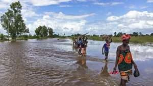 epaselect epa08218573 People wade through a flooded road after heavy rainfall caused severe floods in the coastal city of Beira, Sofala Province, central Mozambique, 14 February 2020. Flooding during the current rainy season, which lasts between October and April, has killed at least 54 people so far and affected some 65,000 people, many of whose homes have been flooded, according to data from the National Institute of Disaster Management (INGC).  EPA/ANDRE CATUEIRA