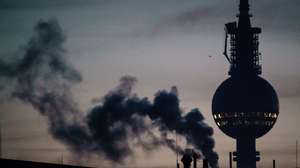 epaselect epa10365104 A chimney smokes in front of the TV tower at dawn time in Berlin, Germany, 14 December 2022. Low winter temperatures in Germany, below zero degrees Celsius, lead to a need for increased heating during cold periods.  EPA/CLEMENS BILAN