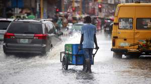 epa10595409 A boy pushes a cart through a flooded road after rain, causing heavy traffic in Lagos, Nigeria 27 April 2023.  EPA/Akintunde Akinleye