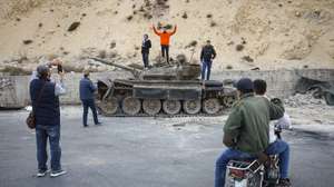 epa11787394 People take pictures of a destroyed military tank in Damascus, Syria, 19 December 2024. Syrian rebels entered Damascus on 08 December 2024 and announced in a televised statement the 'Liberation of the city of Damascus and the overthrow of Bashar al-Assad', as well as the release of all the prisoners.  EPA/ANTONIO PEDRO SANTOS