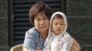 epa10102542 An elderly woman sits with a child in a public square in Shanghai, China, 02 August 2022. China's total fertility rate has dropped below 1.3 percent in recent years. The growth rate has slowed down, and the entire population will see negative growth during the 14th Five-Year Plan period, which is between 2021 and 2025, the National Health Commission reported today. China is expected to enter a stage of severe ageing around 2035, when 60 years old people and above will account for 30 percent of the total population.  EPA/ALEX PLAVEVSKI