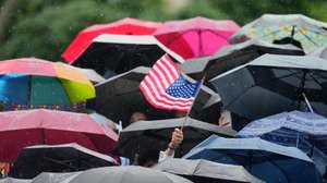 epa12123369 A student waves a US flag among umbrellas during Columbia University's commencement ceremony on Columbia's main campus, in Manhattan, New York, USA, 21 May 2025.  EPA/SETH WENIG / POOL