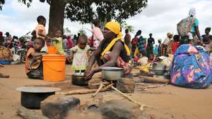 Uma mulher cozinha acompanhada de duas crianças no Centro de Trânsito de Namissir, na Escola Primária Completa dos Coqueiros, que alberga mais de 5.000 famílias deslocadas devido a ataques de grupos armados em Chiúre, na província de Cabo Delgado, norte de Moçambique, 29 de julho de 2025. Vários distritos de Cabo Delgado, sobretudo Chiúre, estão a registar uma crescente atividade por parte de elementos destes grupos nos últimos dias. Na semana passada, extremistas reivindicarem também a decapitação, em locais diferentes, de pelos menos três cristãos moçambicanos. (ACOMPANHA TEXTO DA LUSA DO DIA 09 DE AGOSTO DE 2025). LUÍSA NHANTUMBO