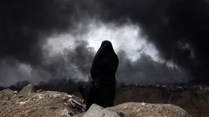 epaselect epa12803513 A veiled Iranian woman, a member of Iran's Red Crescent looks as smoke still rises from Shahran Oil Refinery following last night airstrike in Tehran, Iran, 08 March 2026. A joint Israeli and US military operation continues to target multiple locations across Iran since the early hours of 28 February 2026.  EPA/ABEDIN TAHERKENAREH