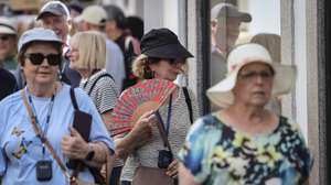 Uma turista usa um leque para se refrescar enquanto passeia no centro histórico de Évora, numa altura em que já se registava temperatura acima dos 35 graus centígrados, Évora, 27 de maio de 2026. O IPMA prevê continuação de temperaturas elevadas para os próximos dias para várias regiões do país com perigo de incêndio muito elevado. NUNO VEIGA/LUSA