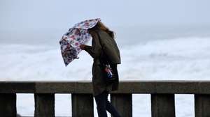 Uma mulher tenta proteger-se da chuva e do vento na marginal da Foz do Douro no Porto, 17 de outubro de 2023. Mais de 40 ocorrências foram registadas desde as 00:00 de hoje, a maioria na Grande Lisboa e em Setúbal, devido ao mau tempo, segundo informação disponível no ‘site’ da Autoridade Nacional de Emergência e Proteção Civil (ANEPC). ESTELA SILVA/LUSA