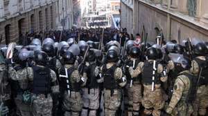 epa11440767 Military police line up in front of supporters of Bolivian President Luis Arce during a protest against military personnel trying to enter the government headquarters in La Paz, Bolivia, 26 June 2024. A group of soldiers led by Bolivian Army general commander Juan Jose Zuniga entered Plaza Murillo on 26 June 2024 using a tank to knock down the door of the government headquarters. The soldiers withdrew after Bolivian President Luis Arce changed the heads of the entire military high command, describing the action as a coup attempt.  EPA/Luis Gandarillas