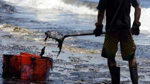 epa04759324 The oil sludge coated boots and shovels of a volunteer worker is shown as he cleans up an oil contaminated beach after an underwater oil pipe ruptured spilling an estimated 21 thousands gallons of oil into the Pacific Ocean near Refugio State Beach, 30 miles north of Santa Barbara, California, USA, 20 May 2015. Dozens of workers plied the four miles stretch of contaminated beach and boats used booms off shore to collect the spilled oil.  EPA/MICHAEL NELSON