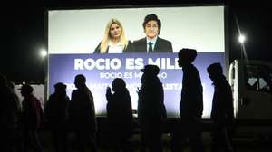 epa12350652 People walk past a fence featuring an image of Argentina's President, Javier Milei, during a campaign closing event for his party, La Libertad Avanza (LLA) in Moreno, Argentina, 03 September 2025.  EPA/Juan Ignacio Roncoroni