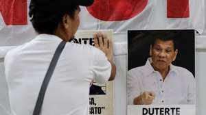 epa12780837 A human rights advocate looks on at an image of former Philippine president Rodrigo Duterte prior to a broadcast of an International Criminal Court (ICC) proceeding from Quezon City, Metro Manila, Philippines, 27 February 2026. Duterte’s confirmation of charges hearing at the ICC at The Hague entered its fourth day on 27 February, as the former leader is facing charges of crimes against humanity resulting from his anti-illegal drugs campaign.  EPA/ROLEX DELA PENA