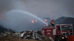 Um bombeiro combate um incêndio que deflagrou hoje à tarde na empresa Tratolixo, em Trajouce, no concelho de Cascais, 10 de julho de 2021. De acordo com fonte do Comando Distrital de Operações de Socorro (CDOS) de Lisboa, o alerta para o fogo na empresa de tratamento de resíduos sólidos Tratolixo, que entretanto se estendeu a uma zona de mato, foi dado às 16:15 e às 20:30 segundo a Autoridade Nacional de Emergência e Proteção Civil estão no terreno 154 operacionais , apoiados por 56 veículos. RODRIGO ANTUNES/LUSA