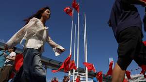 epa13274336 People walk pass Chinses and Hong Kong flags in Hong Kong, China, 01 October, 2026. The city celebrates China's National Day on 01 October 2026, marking the 77th founding anniversary of the People's Republic of China.  EPA/MAY JAMES