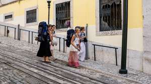 Turistas observam o local onde se deu o descarrilamento seguido de queda livre e colisão do histórico elevador da Glória, durante a homenagem às vítimas do acidente no elevador da Glória, organizada pelo Sindicato dos Trabalhadores de Transportes Rodoviários e Urbanos de Portugal, filiado na Federação dos Sindicatos de Transportes e Comunicações, em Lisboa, 03 de setembro de 2026. O histórico ascensor descarrilou a 03 de setembro de 2025, provocando 16 mortos e 24 feridos, de 15 nacionalidades. JOSÉ SENA GOULÃO/LUSA