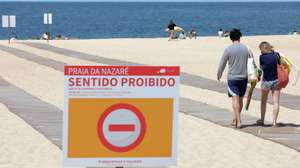 Turistas caminham na praia onde sem sol e com poucos banhistas, a época balnear arrancou hoje com mais gente na marginal e nas esplanadas do que na praia da Nazaré, onde não falta espaço para cumprir distâncias de segurança, Nazaré, Leiria, 6 de junho de 2020. Com algumas nuvens a toldar o sol e a tornar a praia menos convidativa, era na marginal da Nazaré que manhã cedo se concentrava o movimento, com passeantes e atletas a cruzarem-se no passeio largo. PAULO CUNHA /LUSA