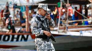 epa11340974 An armed Filipino coastguard personnel holds a radio as he stands guard next to a motorized wooden boat before they sail along Masinloc Bay on their voyage to Scarborough shoal, in the vicinity of Masinloc town, Zambales province, Philippines, 15 May 2024. A civilian-led mission joined by at least a hundred fishermen embarked on Scarborough Shoal in the disputed South China Sea to assert the Philippines’ territorial claim. Scarborough Shoal (‘Bajo de Masinloc’ called by Filipino fishermen), a fishing haven shoal within the Philippine maritime territory that China occupied a decade ago, was recently reported to be driving away Filipino fishermen by Chinese coastguard ships.  EPA/FRANCIS R. MALASIG