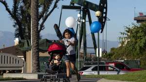 epa07874195 Kids play in the Hilltop Park next to a pumpjack in Signal Hill, Los Angeles, California, 14 August 2019.  (issued 27 September 2019) With nearly 6,000 active oil and gas wells in the county, according to a Natural Resources Defense Council, Los Angeles remains the largest urban oil field in the US. Of the 18 million people leaving in greater Los Angeles, 600,000 live less than 400 meters from an active well.  The story of the city is deeply intertwined with the oil industry. Old documents show Venice Beach covered with rigs and people walking the streets wearing gasmasks because the air pollution was so intense. This situation led to California being able to edict its own gas emission standards, stricter than those in the rest of the country, to counter the disastrous impact of the combined effects of oil production and traffic. This status was recently revoked by President Trump, a decision that is currently being challenged by the state of California.  EPA/ETIENNE LAURENT