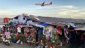 epa11944074 An elderly woman sits next to shanties as a Philippine Airlines (PAL) plane flies over a slum area in Paranaque city, Metro Manila, Philippines, 06 March 2025. According to the latest report of the Philippine Statistics Authority (PSA), poverty rate dropped to 15.5 percent in 2024 from 18.1 percent in 2021, with 17.54 million people living below the poverty line, a decrease of 2.4 million from the previous survey two years earlier.  EPA/FRANCIS R. MALASIG