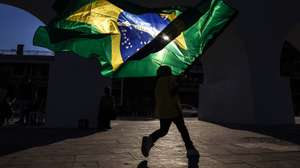 epa13025293 A boy runs with the Brazilian flag during a barber competition in Rio de Janeiro, Brazil, 08 June 2026. The Brazilian city of Rio de Janeiro hosted an international barber competition in which professionals showcased the latest haircut trends, many of which were inspired by the upcoming 2026 FIFA World Cup.  EPA/ANTONIO LACERDA
