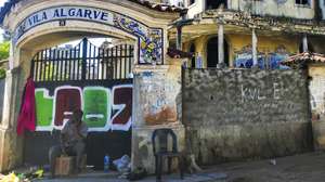 Celestino, sapateiro, encontrou na sombra da entrada da Vila Algarve, Maputo, o local para trabalhar, alheio às histórias de terror das ruínas da antiga prisão da PIDE a que 50 anos de independência não conseguiram dar nova vida, Maputo, Moçambique, 26 de maio de 2025. (ACOMPANHA TEXTO DA LUSA DE 23-06-2025) LUÍSA NHANTUMBO/LUSA