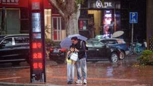 epaselect epa11695505 People shelter under an umbrella as they wait at a traffic light during heavy rain due to Typhoon Kong-rey in Shanghai, China, 01 November 2024. After sweeping through Taiwan on 31 October, Typhoon Kong-rey is approaching China's east coast, with Shanghai bracing for heavy rainfall and strong winds. Some high-speed train services were suspended starting from 31 October and citizens were alerted by authorities to stock up on drinking water and food.  EPA/ALEX PLAVEVSKI