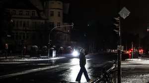 epaselect epa12626515 A pedestrian walks on a darkened street in the Zehlendorf district in southwest Berlin, Germany, 04 January 2026. According to state-owned operator Stromnetz Berlin, a large-scale power outage in southwest Berlin, caused by a suspected arson attack on the Teltow Canal cable bridge, has been affecting about 45,000 households since 03 January 2026 as freezing temperatures grip the city.  EPA/FILIP SINGER