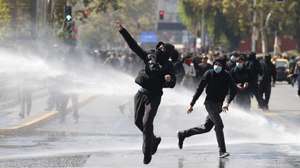 epa12851809 Protesters and members of the Chilean National Police’s riot squad clash during a demonstration in Santiago, Chile, 26 March 2026. The Chilean government has sealed off the capital’s downtown area with barricades, closed subway stations, rerouted traffic, and deployed a massive police presence to prevent protests over the implementation of the historic fuel price hike announced on 24 March.  EPA/Elvis Gonzalez