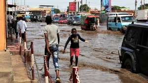 epa10579121 Locals walk next to flood waters caused by rainfall in Luanda, Angola, 18 April 2023. Since last week the rains that fell in Luanda area have caused the death of at least seven people, including three children in the early hours of 18 April, in addition to falling trees, thousands of flooded homes and collapsed electricity pylons.  EPA/AMPE ROGERIO