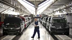 Um trabalhador da fábrica Autoeuropa do grupo alemão Volkswagen passa pela linha de sáida de veículos produzidos numa altura em que se celebram os 20 anos do início da produção da Autoeuropa em Portugal, em Palmela, concelho de Setúbal, 26 de abril de 2015. (ACOMPANHA TEXTO) MÁRIO CRUZ/LUSA