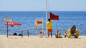 Um nadador-salvador da praia de Quarteira retira a bandeira vermelha, que interditava os turistas a banhos devido à presença de bactérias prejudiciais à saúde na água do mar, para hastear a bandeira verde que permite os banhos, após nova análise à qualidade da água nas praias de Quarteira e Vale do Lobo, em Loulé, 26 de julho de 2023. A interdição a banhos nas praias de Quarteira e Vale do Lobo, no Algarve, que durou menos de 24 horas e cuja interdição foi hoje levantada, foi causada por um foco de poluição. RICARDO NASCIMENTO/LUSA
