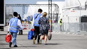 epa10638804 Workers help a woman with her luggage as she arrives at the centre for Ukrainian refugees, at the former Berlin Tegel Airport, in Berlin, Germany, 19 May 2023. The German Red Cross (DRK) has set up an arrival center for refugees in response to their massive arrival in Germany, at the beginning of the Ukrainian crisis in March 2022.  EPA/FILIP SINGER