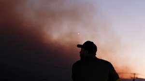 epa11599332 A gas station worker looks out as the Bridge Fire continues to burn in Pinon Hills, California, USA, 11 September 2024. The Bridge Fire, which has now burned more than 47,000 acres in Angeles National Forest, is one of three large wildfires currently burning in Southern California after igniting amid a heat wave in the region.  EPA/CAROLINE BREHMAN