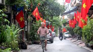 epa11577436 A man rides a bicycle under Vietnamese national flags at an alley in Hanoi, Vietnam, 01 September 2024. Vietnam will celebrate the 79th anniversary of National Day on 02 September.  EPA/LUONG THAI LINH