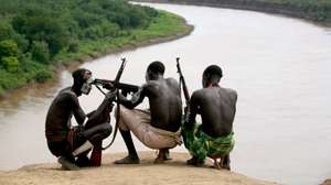epa01147322 A picture dated 06 October 2007 shows members of the Karo tribe sit above with rifles the Omo River at the Kenya border in the area of Murle. The Kara, who number only about 3,000 people, mainly live on the practice of flood retreat cultivation on the banks of the Omo River in South-western Ethiopia. Many members of this ethnicity are Muslims.  EPA/PAVEL WOLBERG