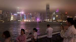 epa10542524 People look at lilluminated buildings across Victoria Harbour on Hong Kong island a few minutes before Earth Hour in Hong Kong, China, 25 March 2023. During Earth Hour many buildings along the Victoria Harbour waterfront switch off their lights and go dark for an hour. Earth Hour was originally started in 2007 in Sydney by the World Wildlife Fund and is now a global movement in which millions participate to demonstrate the need for greater action on climate change and energy saving.  EPA/JEROME FAVRE
