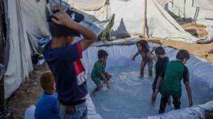 epa13117806 Displaced Palestinian children play in a makeshift pool to cool down on a hot summer day at a tent camp in eastern Gaza City, 17 July 2026. Since 07 October 2023, up to 1.7 million people, or more than 75 percent of the population, have been displaced throughout the Gaza Strip, some more than once, in search of safety, according to the United Nations Relief and Works Agency for Palestine Refugees in the Near East (UNRWA).  EPA/MOHAMMED SABER