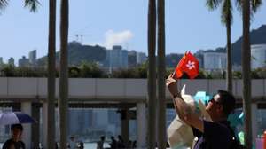 epa13274328 A man holds the flags of China and Hong Kong in Hong Kong, China, 01 October, 2026. The city celebrates China's National Day on 01 October 2026, marking the 77th founding anniversary of the People's Republic of China.  EPA/MAY JAMES