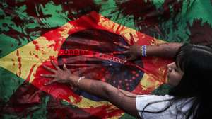 epa10663928 A Brazil national flag is smeared in red paint as indigenous people protest against a bill that makes it difficult to demarcate land in Brazil, at the Ministries Esplanade, in Brasilia, Brazil, 30 May 2023. A group of indigenous people of the Guarani ethnic group blocked one of the main highways of Sao Paulo, the most populous of the Brazilian states, in protest against a bill that is being processed in Congress and that could make it difficult to demarcate the native lands.  EPA/ANDRE COELHO