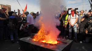epa13341478 Protesters stand around a burning tank mockup during a demonstration and a general strike organized by the USB union in Naples, Italy, 30 October 2026. Workers and students protest against war, the economic situation, and the rising cost of living.  EPA/CESARE ABBATE